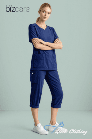 Female model wearing dark blue medical scrubs with pockets, arms crossed, standing against a light green background. Bizcare logo at top left and Luna Clothing script at lower right.