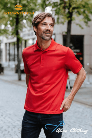 Man in a red polo shirt standing on a city street, smiling; Stormtech logo in the top-left and Acee Clothing script logo bottom-right.