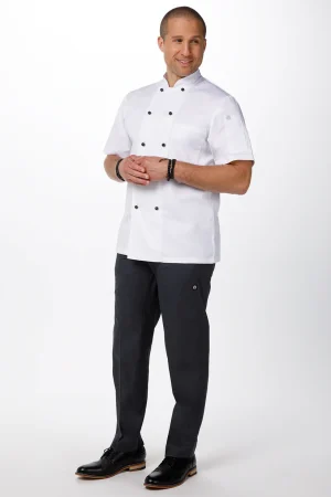 Male chef in a white double-breasted jacket, dark pants, and black shoes, posing with hands together.