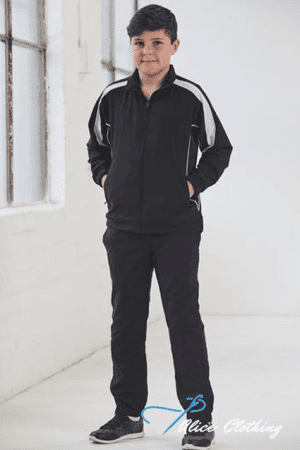 Boy in a black tracksuit with white stripes, standing with hands in pockets in a bright studio.