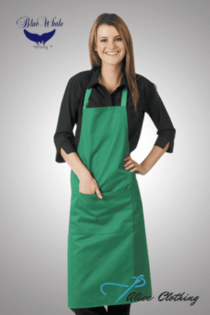Smiling woman wearing a green kitchen apron over a black blouse, posing with hands on her hips.