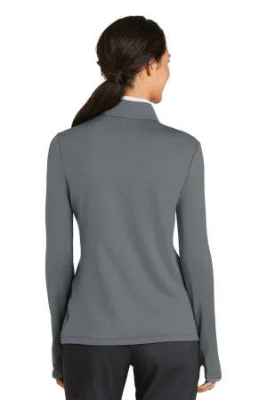 Back view of a woman wearing a gray long-sleeve jacket, standing in dark pants.