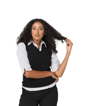 Woman with curly hair wearing a striped shirt and black vest, touching her hair while looking at the camera.