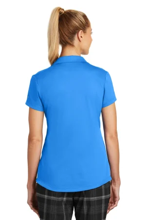 Back view of a woman wearing a bright blue polo shirt with short sleeves and dark plaid pants, ponytail.