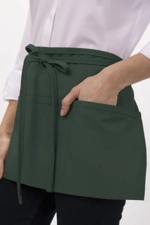 Green wrap waist apron with a tied belt and front pocket, worn by a person with a white shirt.