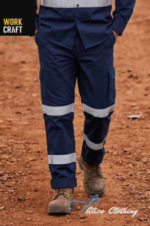 Person wearing navy cargo work pants with reflective bands on knees and calves, brown boots, standing on dirt; logos for Work Craft and Alice Clothing visible.