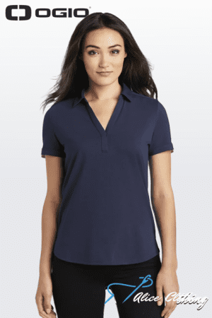 Female model wearing a navy polo shirt against a light gradient backdrop, with the OGIO logo in the top-left corner.