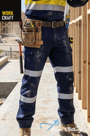 Construction worker in blue reflective pants with white bands, tool belt, at a wooden-framed construction site; WORK CRAFT and Alice Clothing logos visible.