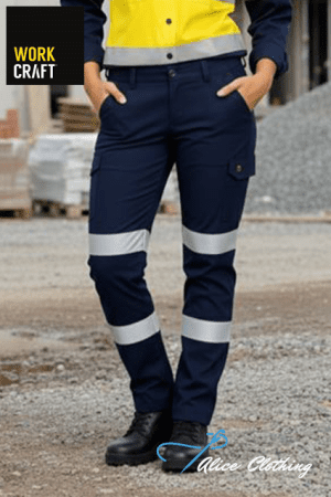 Close-up of a construction worker wearing navy cargo pants with reflective bands around the knees and shins on a gravel site.