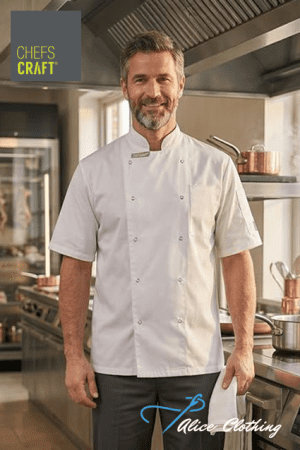 Professional chef in a white double-breasted jacket stands in a commercial kitchen, with Chef's Craft branding visible on the upper left.