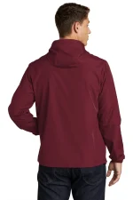 Man wearing a burgundy hooded jacket, shown from the back with one hand resting on hip, dark jeans visible.