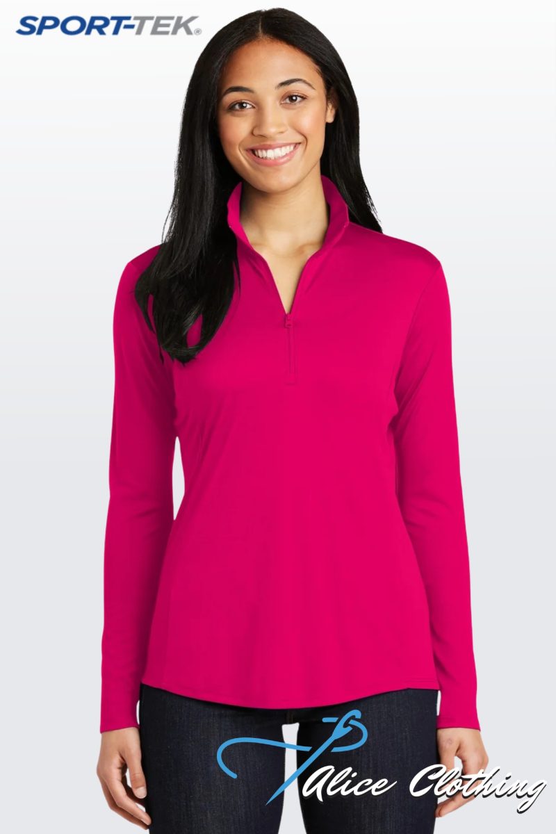 Portrait of a woman smiling in a bright pink long-sleeve pullover, standing against a light gradient background; SPORT-TEK logo in the top-left corner and 'Alice Clothing' graphic on dark jeans.