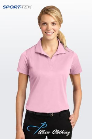 Smiling woman modeling a light pink polo shirt against a pale gradient background; SPORT-TEK logo top left and Alice Clothing logo bottom.