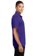 Side view of a man wearing a purple polo shirt and black pants, smiling against a white background.